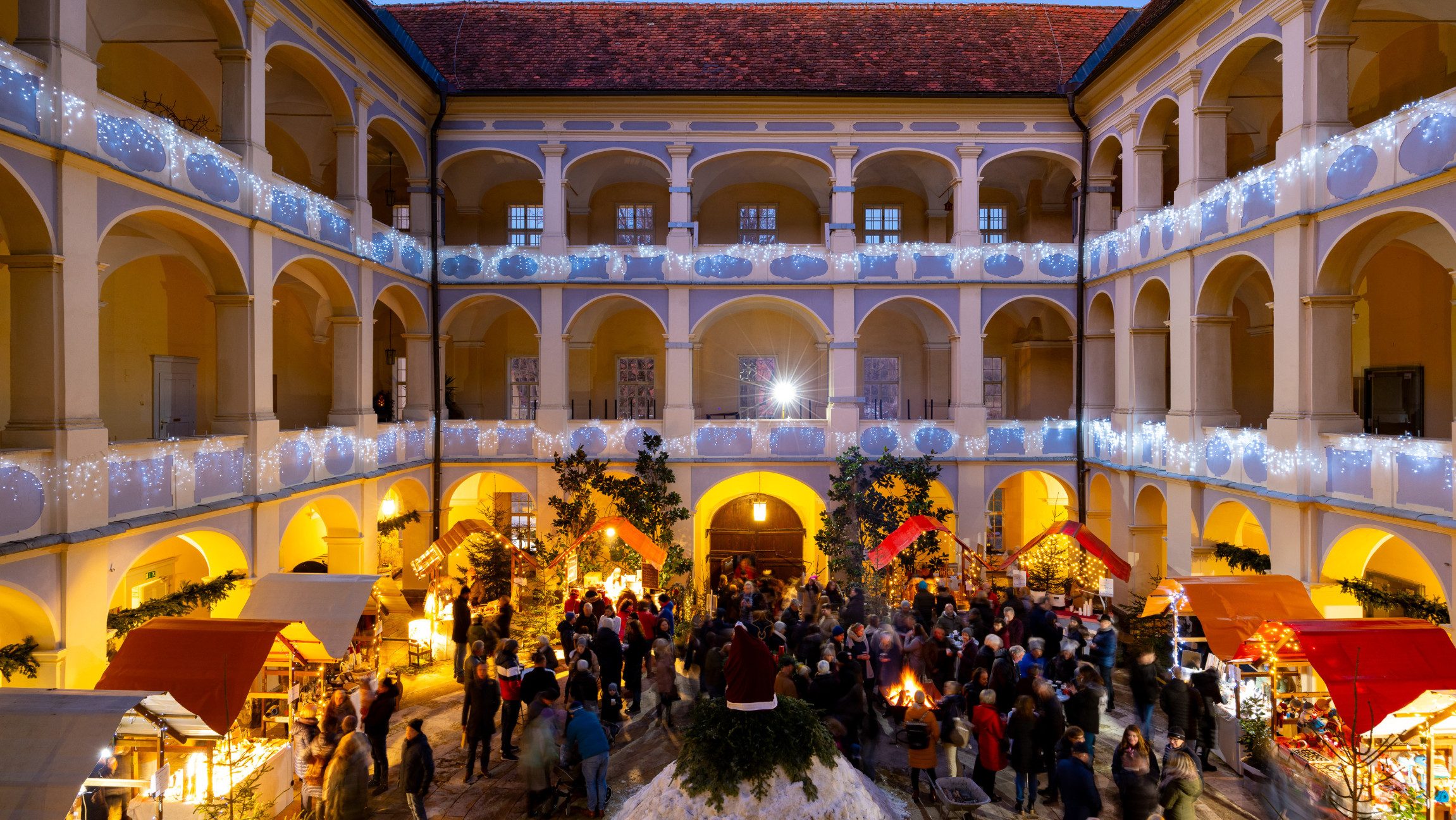 Blick von oben in einen Innenhof in dem ein Adventmarkt stattfindet.