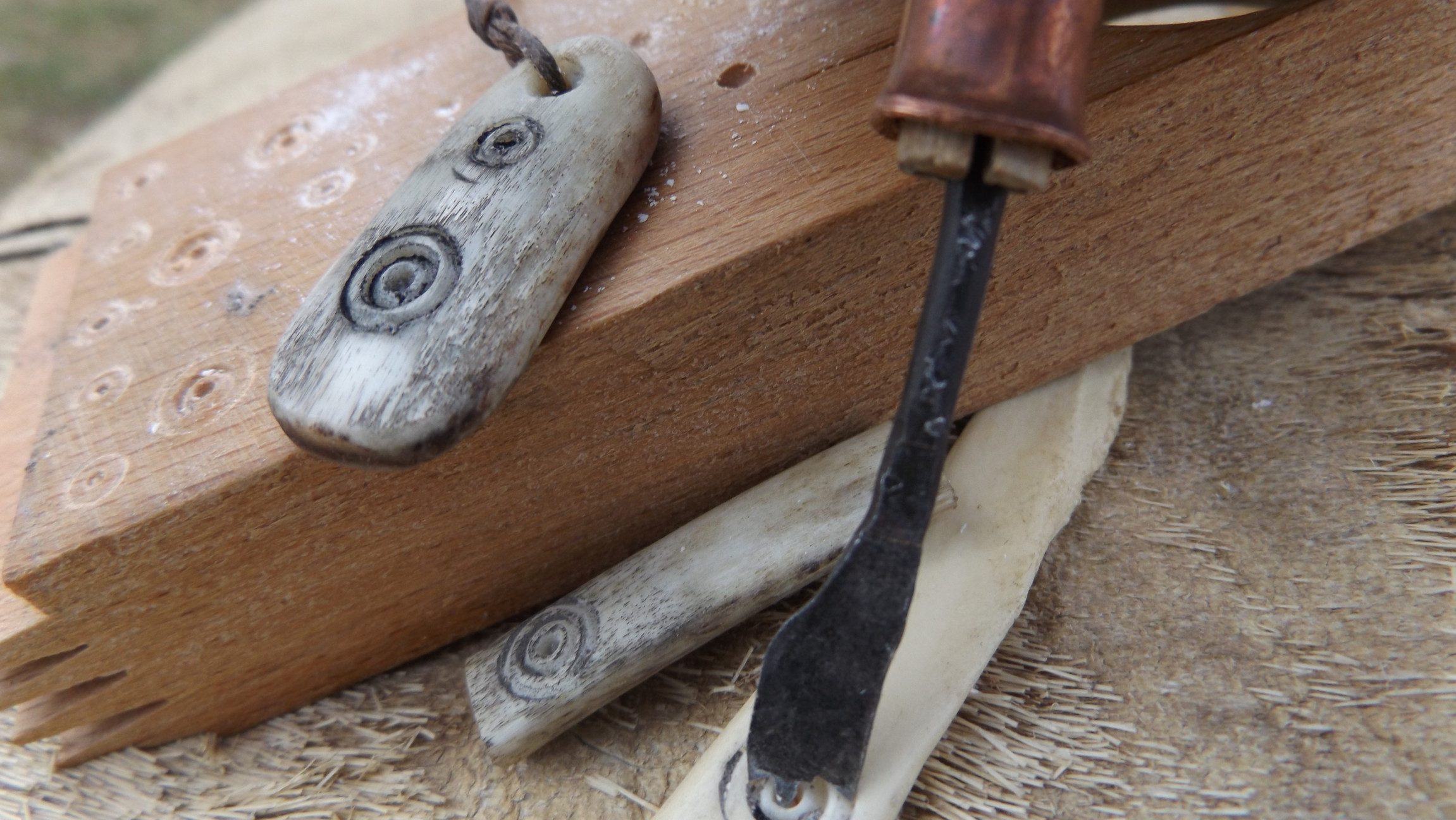 Blick auf einen Hobel, der bei Steinen und einem Holzblock liegt.