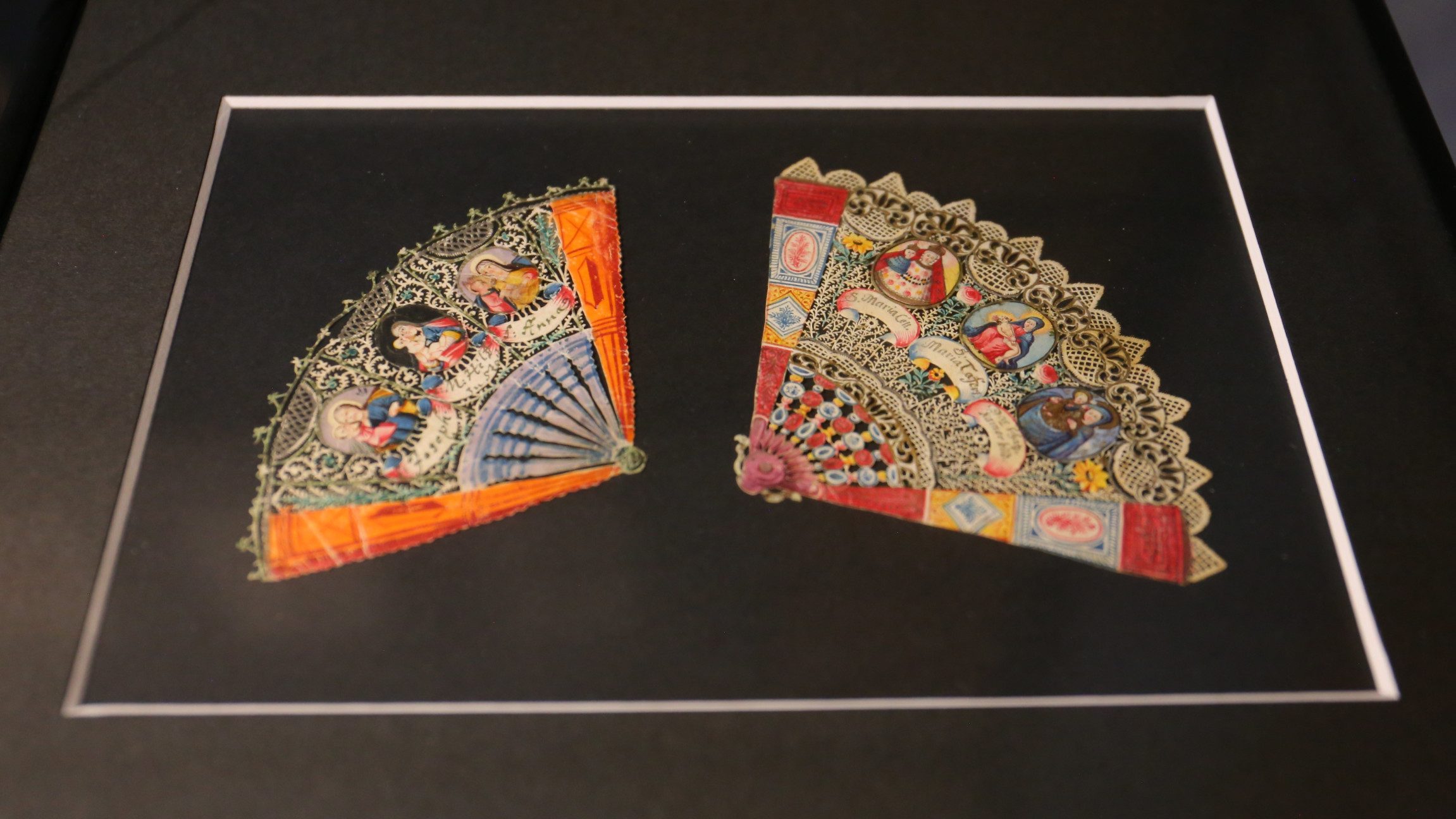 Foto von zwei bunten Fächern auf schwarzem Hintergrund.