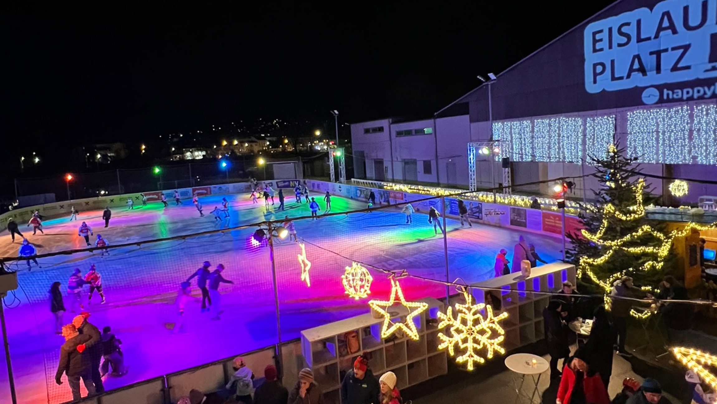 Bunt beleuchteter Eislaufplatz auf dem Menschen eislaufen.
