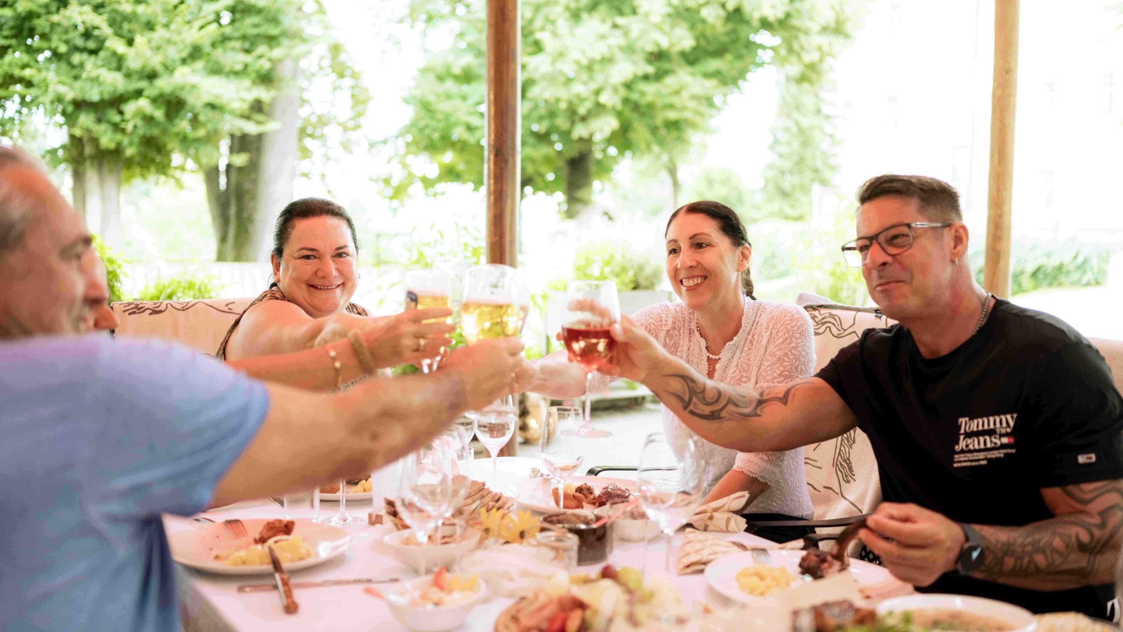 Fröhliche Gäste am Tisch mit einem Glas Wein beim Sommerabend in Piber.