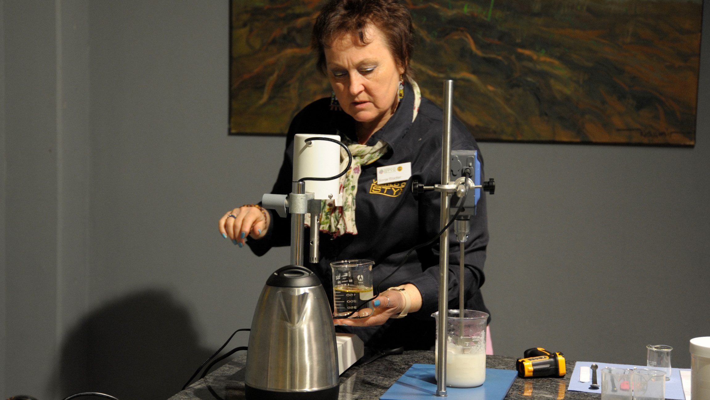 Foto einer Dame die an einer Maschine kurbelt und etwas in ein Glas abfüllt.