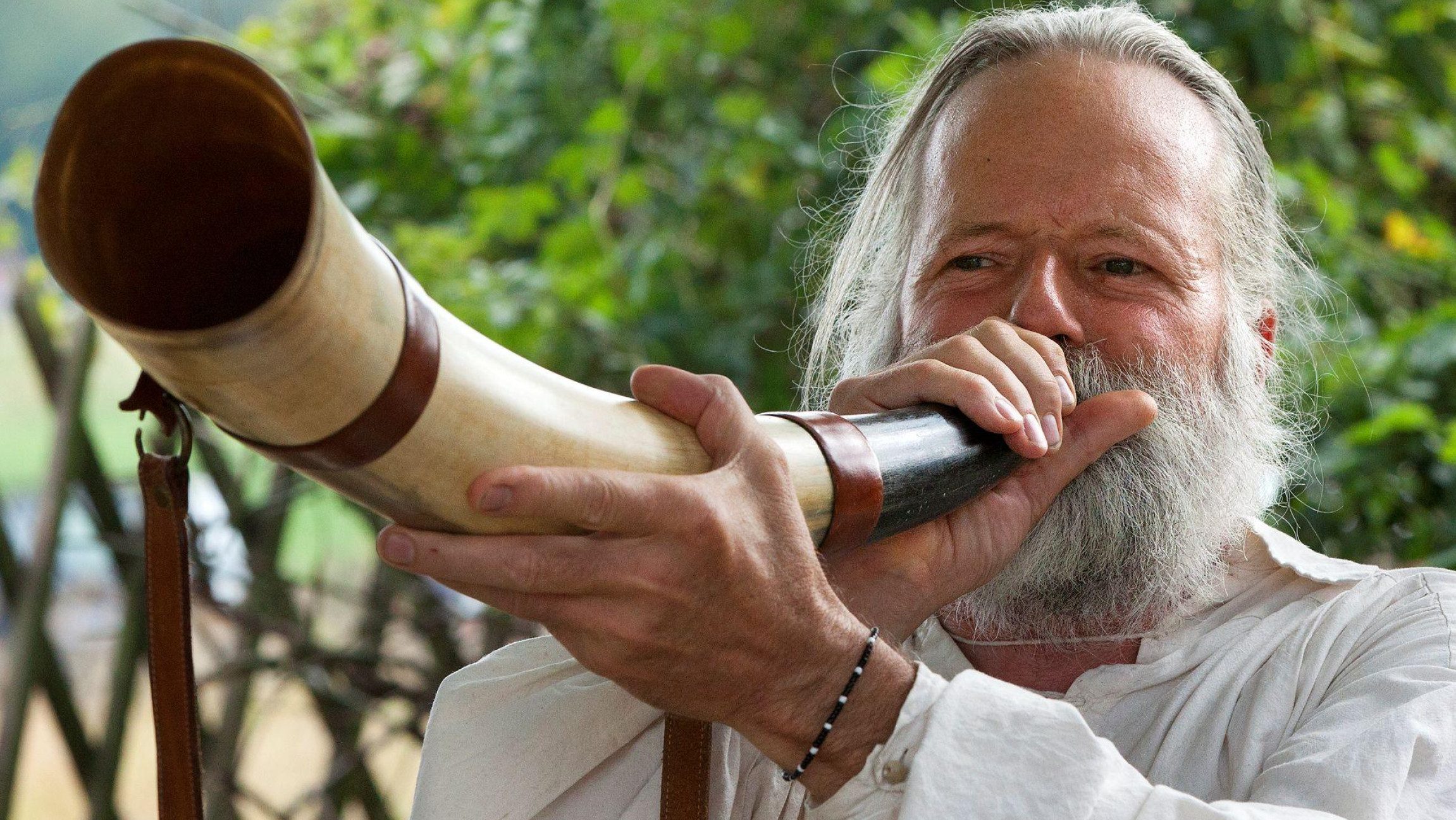 Foto von einem Mann der durch ein Horn bläst, um zu musizieren.