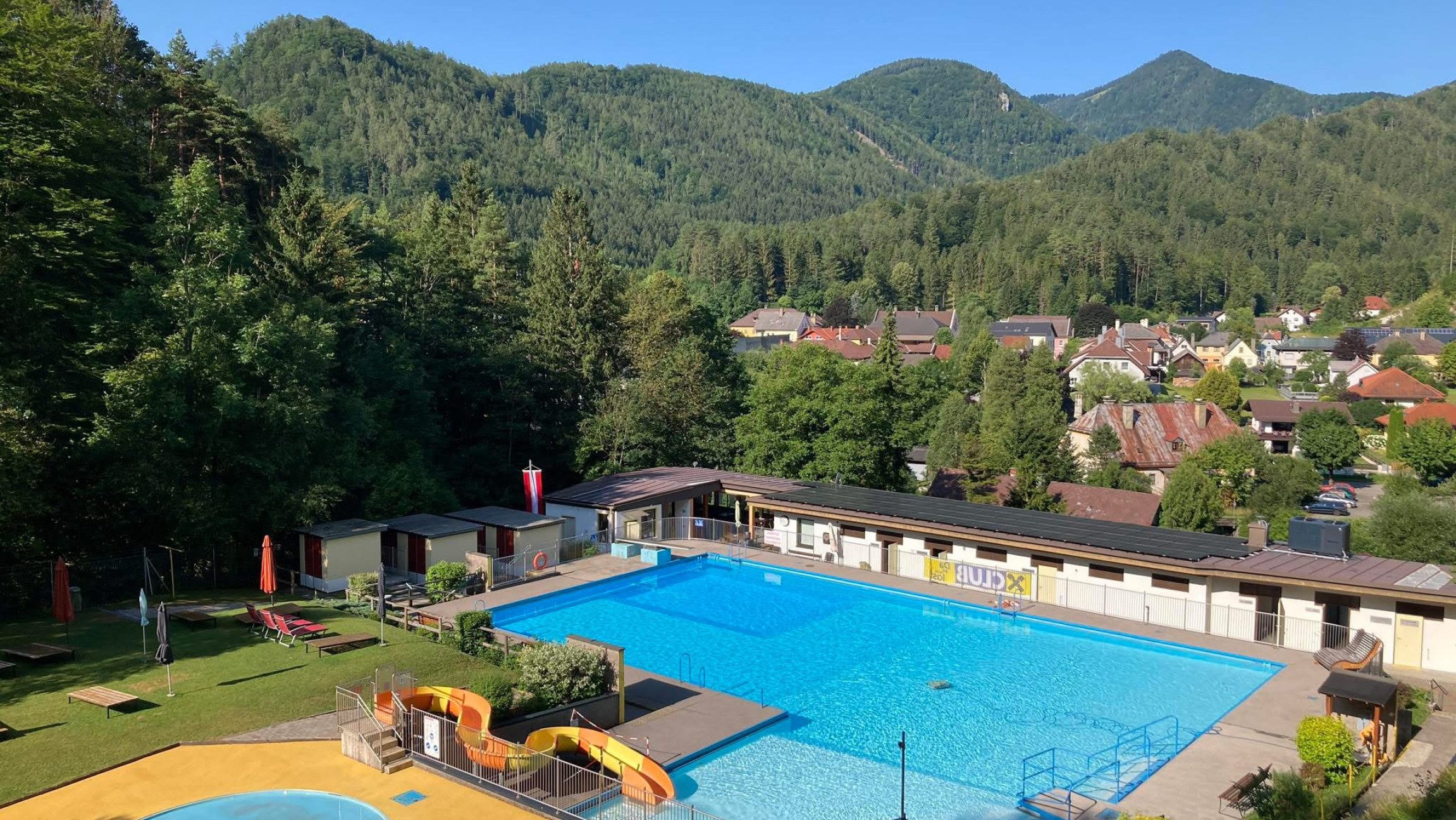 Blick auf das Voralpenbad Hohenberg mit einem Schwimmbecken und einer Rutsche.