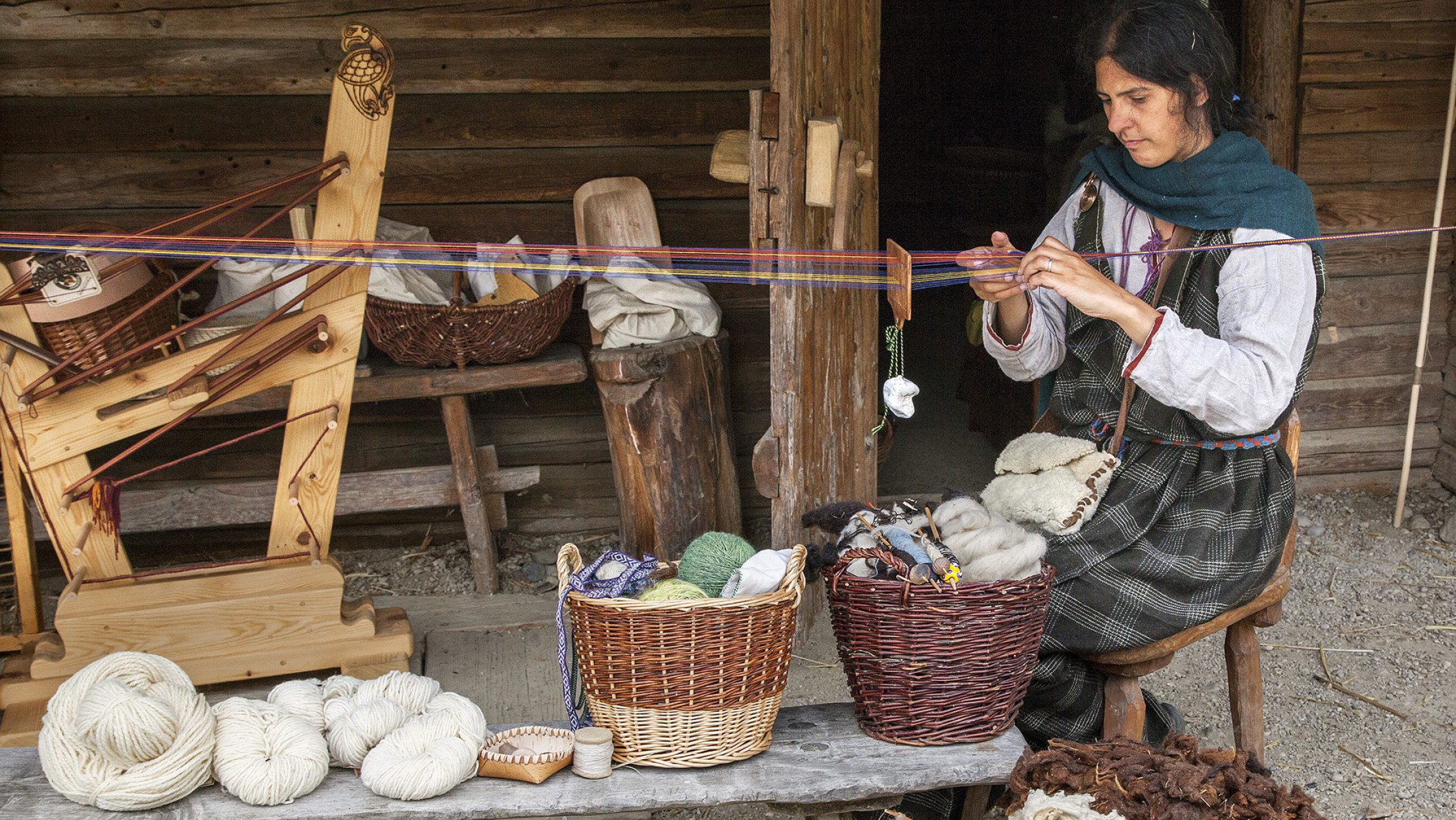 Blick auf eine Dame, die Wolle spinnt.
