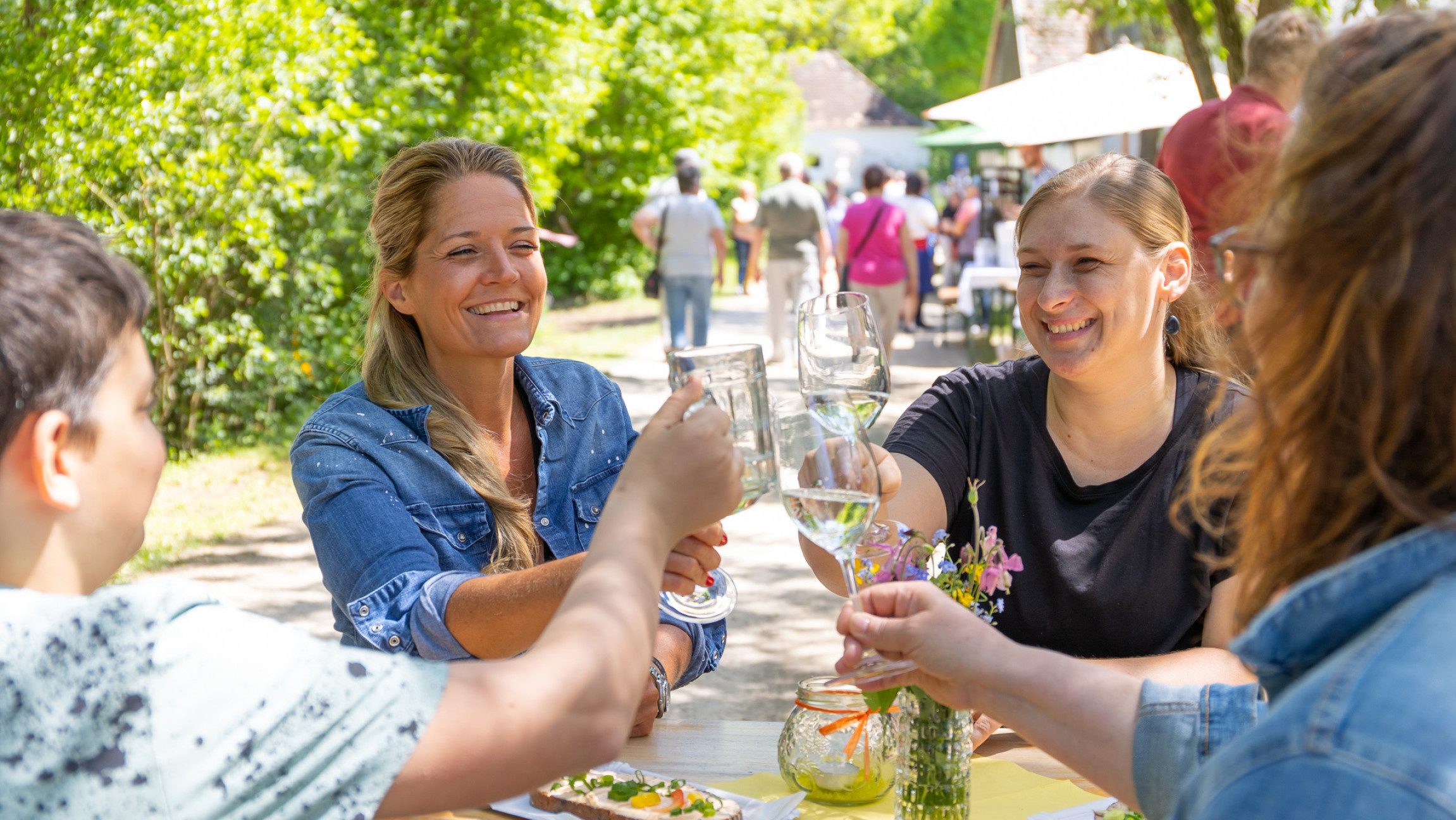 Blick auf vier Frauen, die bei einem Stehtisch stehen und anstoßen.