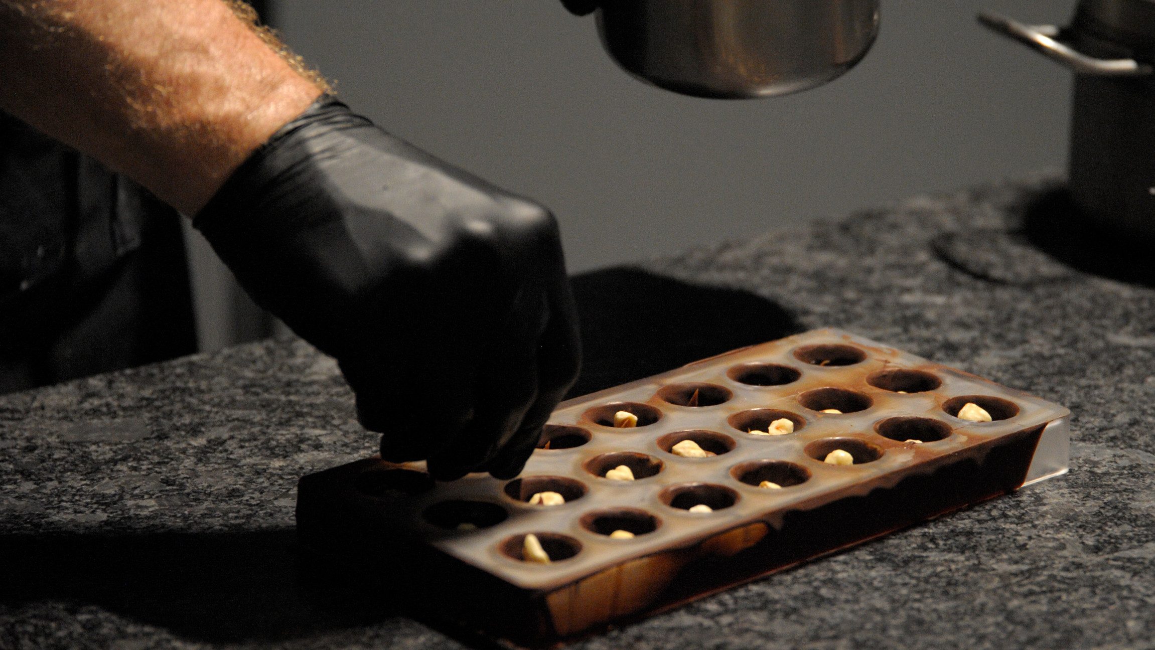 Foto einer Hand die Nüsse in eine Pralinenform legt.