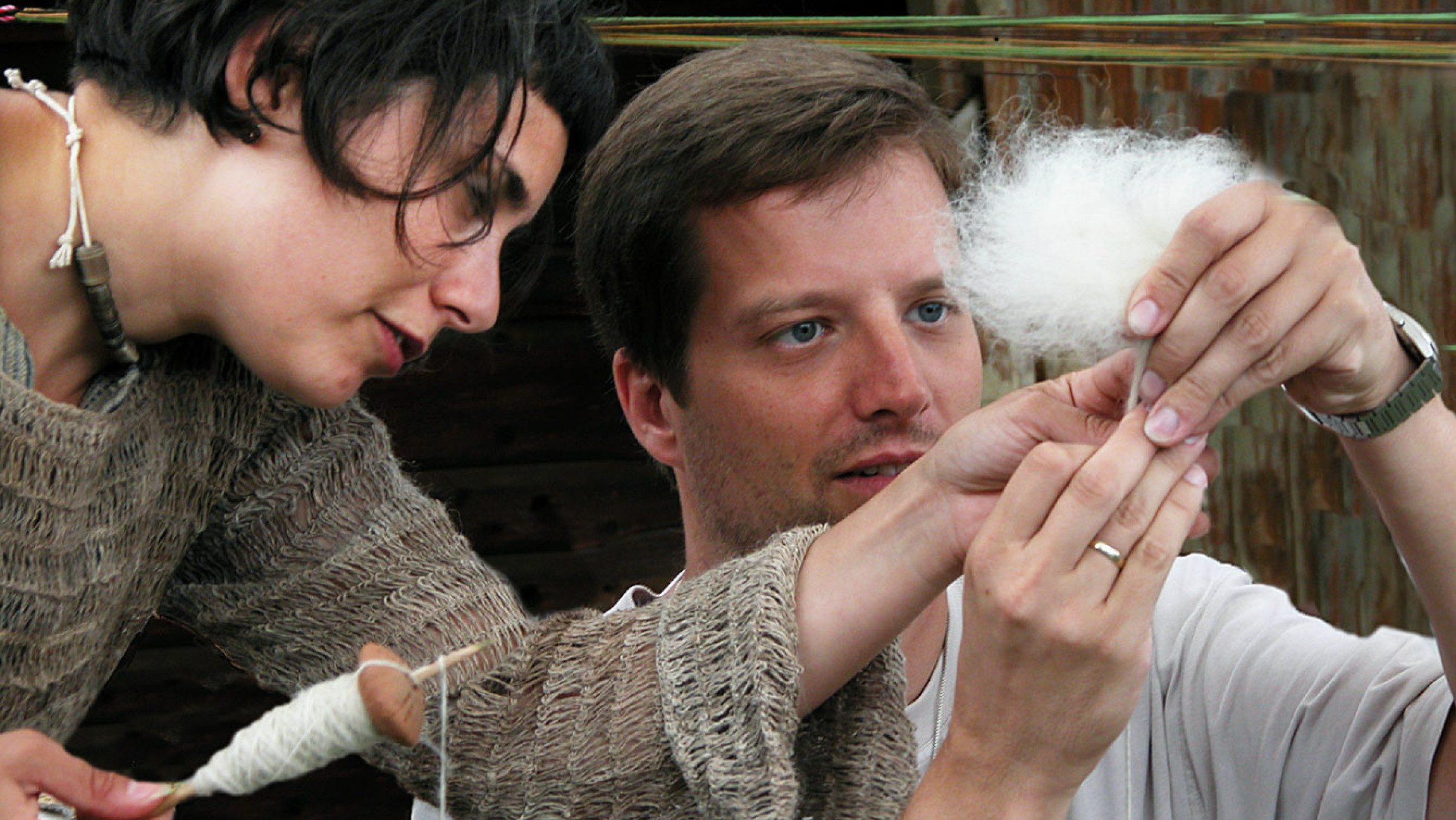 Foto von zwei Erwachsenen die Wolle spinnen.