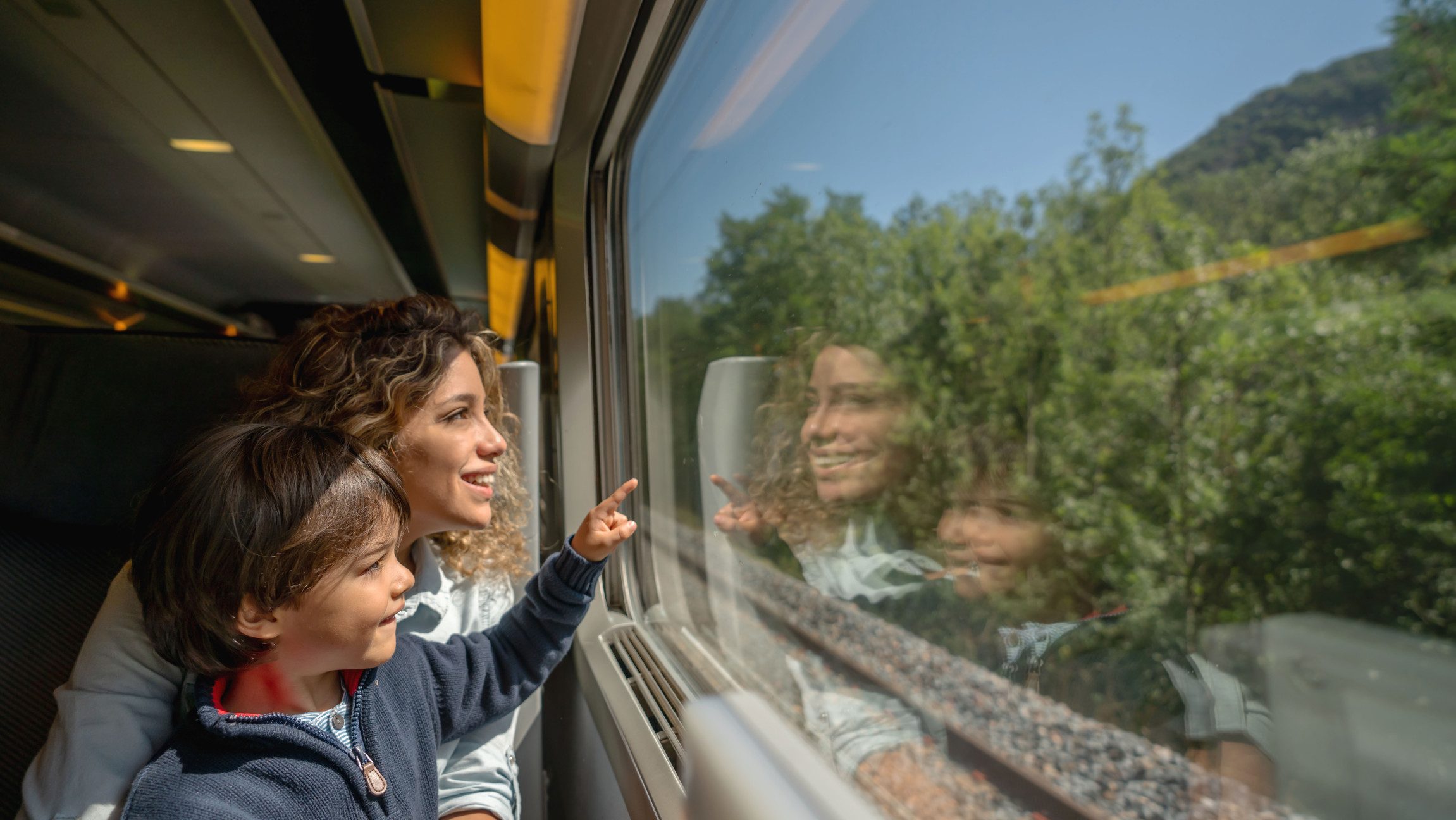 Foto von einer Mutter mit ihrem Kind, das aus dem Zugfenster blickt.