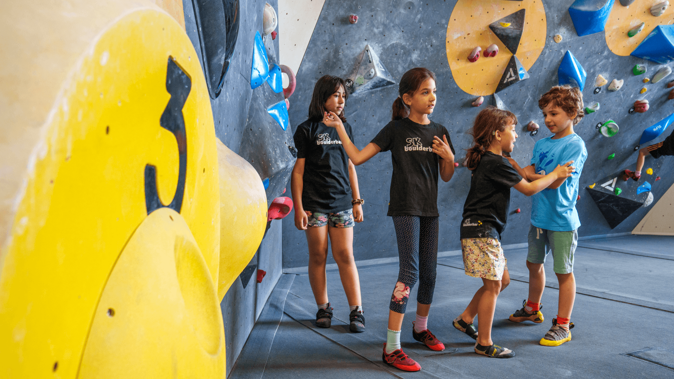Foto von 4 Kindern die in einer Boulderhalle stehen.