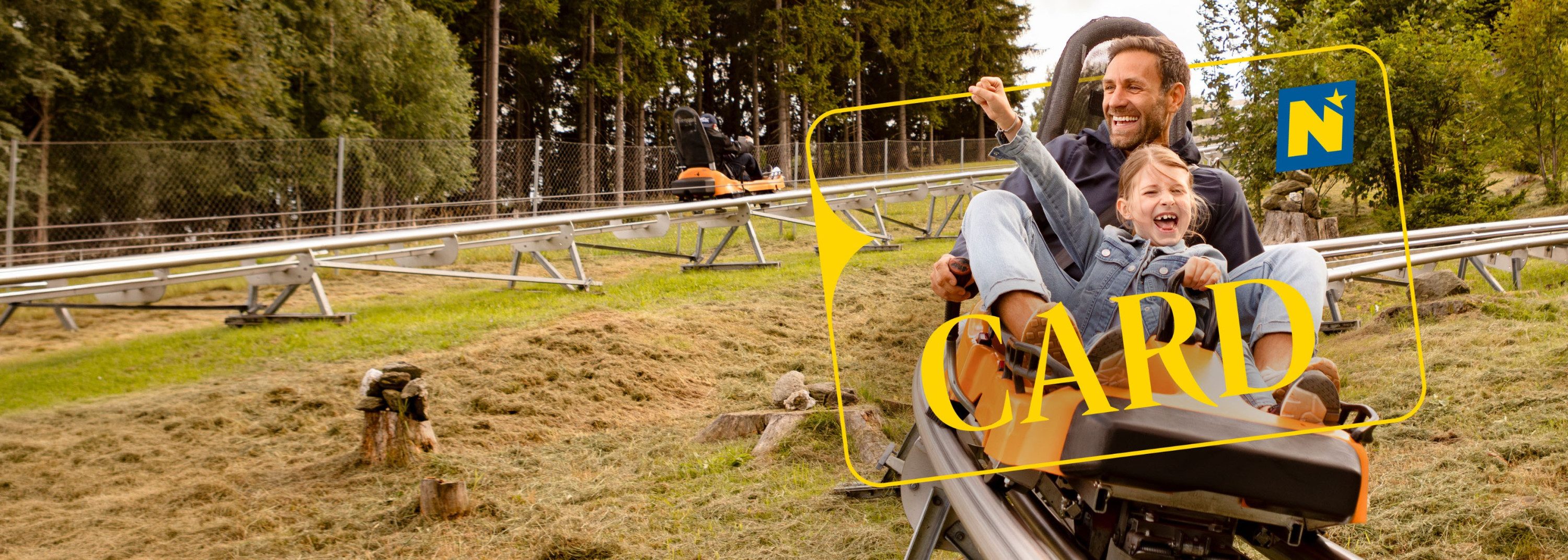 Vater und Kind fahren auf der Sommerrodelbahn und haben Spaß