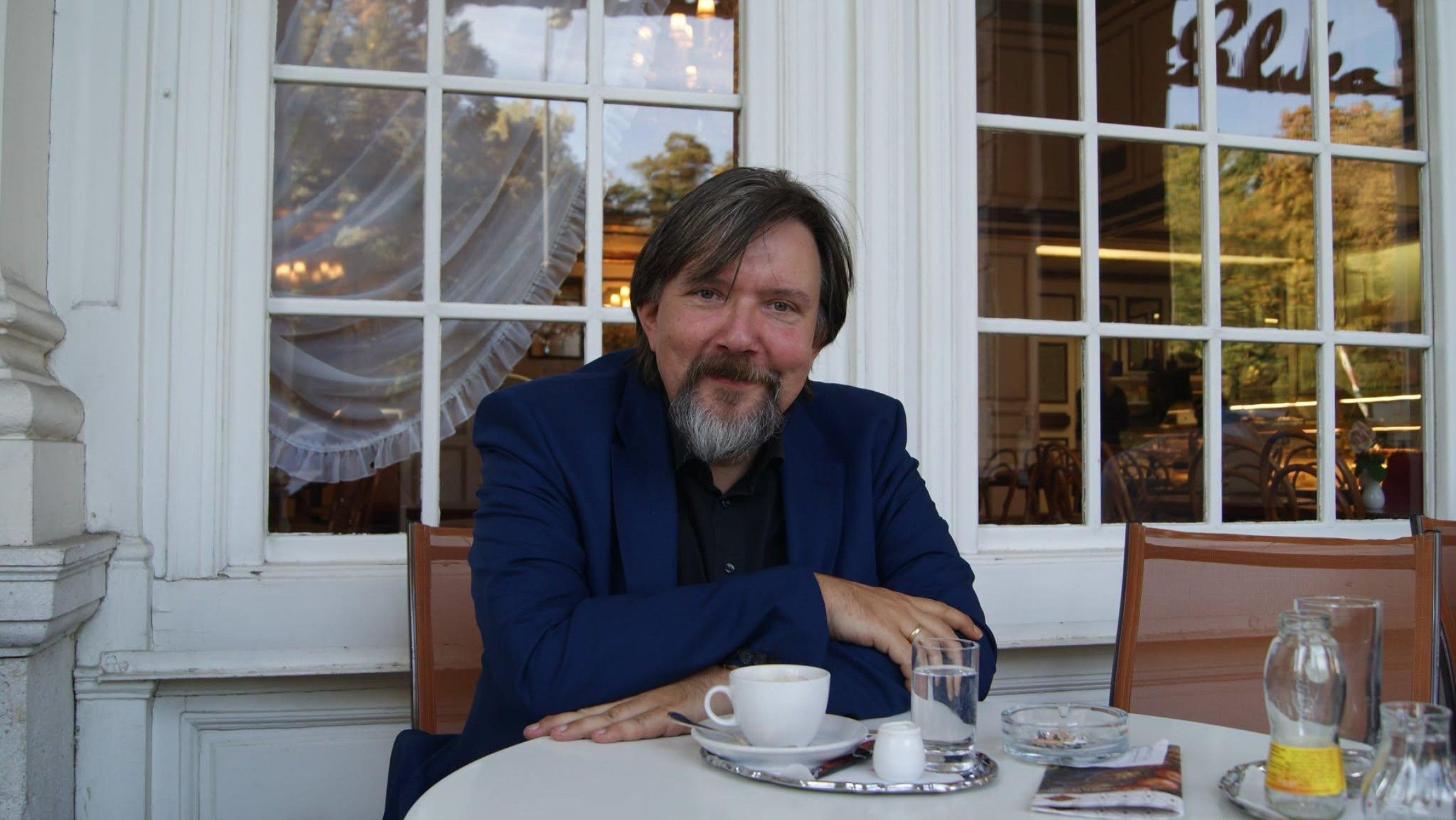 Der Autor Andreas Pittler sitzt an einem Kaffeetisch.