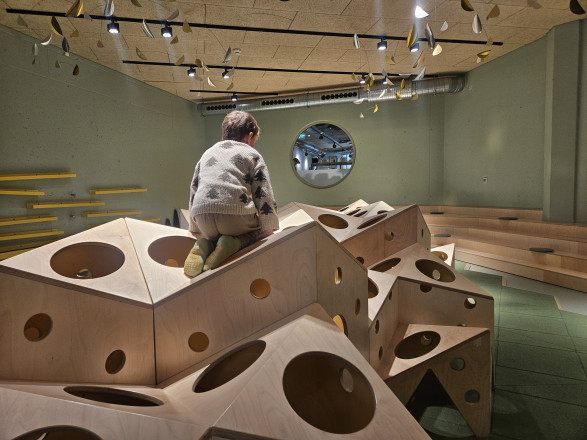 Junge der auf einer Installation aus Holz sitzt