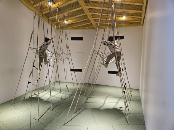 Junge der auf einem Klettergerüst aus Seilen klettert