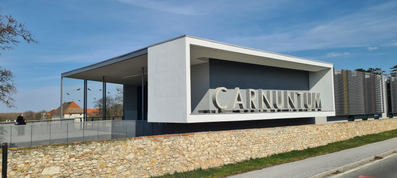 Modernes Besucherzentrum der Römerstadt Carnuntum mit großem Schriftzug „Carnuntum“. Das Gebäude verbindet zeitgenössische Architektur mit der historischen Ausgrabungsstätte.