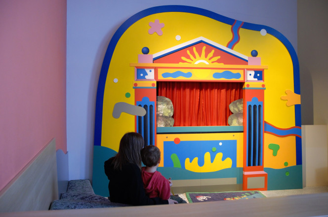 Frau mit Kind blicken auf Puppentheater