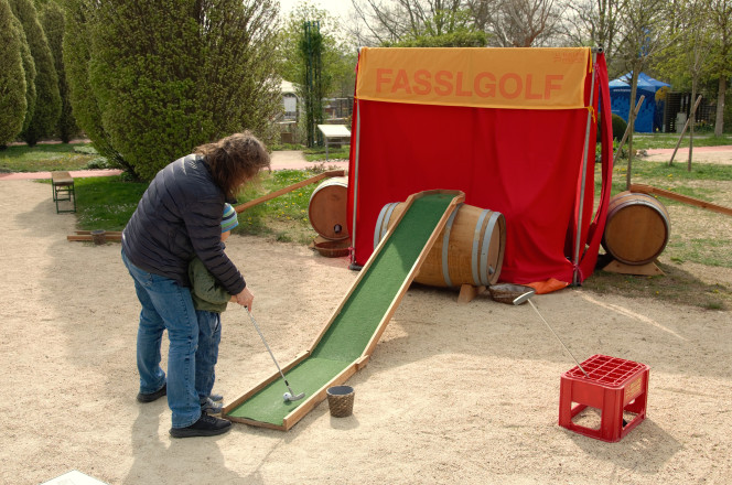 Frau spielt mit Kind Minigolf.