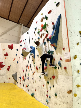 Junge der auf eine bunte Kletterwand klettert