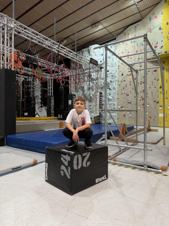 Junge sitzt auf einem Hocker vor einem Ninja-Pacour in der Monkey Factory Wolkersdorf