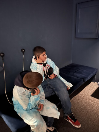 Zwei Jungs die auf einem schmalen Bett sitzen und sich je ein Telefon mit der Hand ans Ohr halten