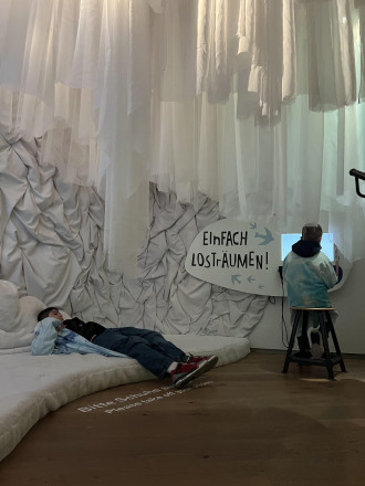 Ein in weiß und blau Tönen gestalteter Raum mir einer Couch in Wolkenform und zwei Jungs