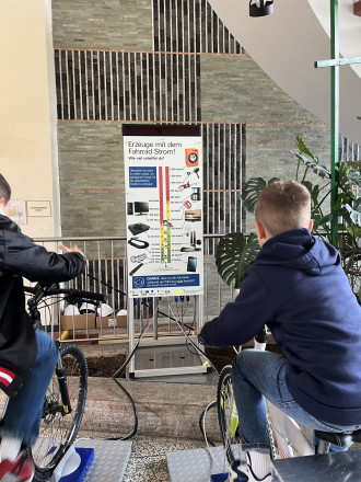 Zwei Jungs die auf Fahrrädern sitzen, randeln und damit Strom erzeugen