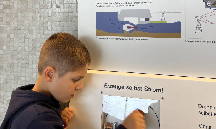 Ein Junge der an einer Kurbel dreht und selbst Strom erzeugt