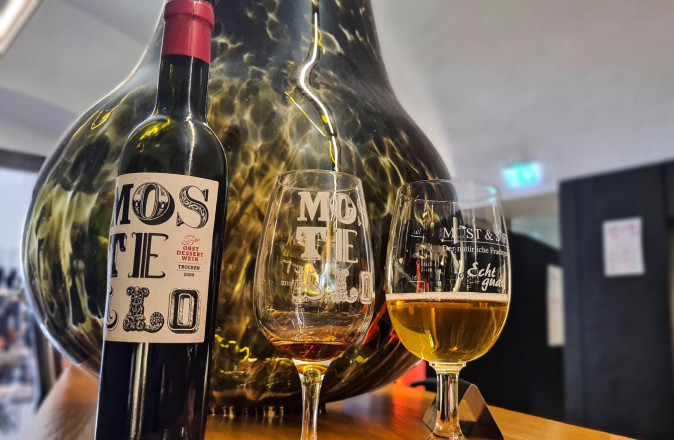 Mostflasche mit zwei befüllten Gläsern rechts davon