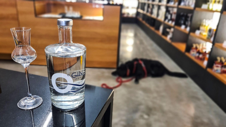 Gin-Glas und Flasche auf Tisch, Shop im Hintergrund