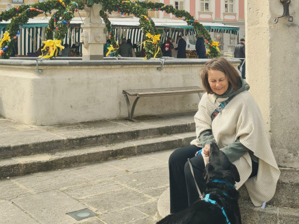Eine Frau sitzt auf einer Steinstufe mit ihrem schwarzen Hund vor ihr