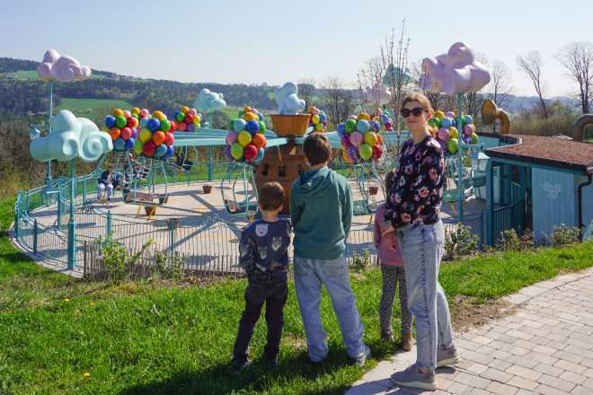 Familie die vor einem Ringelspiel steht im Eis-Greissler Erlebnispark