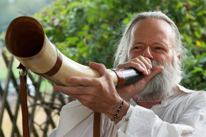 Foto von einem Mann der durch ein Horn bläst, um zu musizieren.