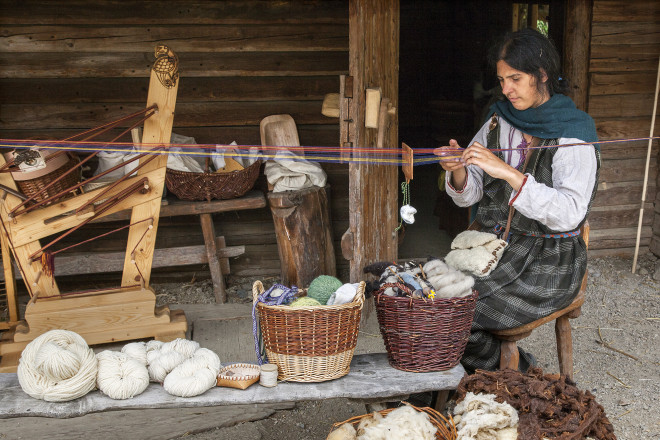 Blick auf eine Dame, die Wolle spinnt.