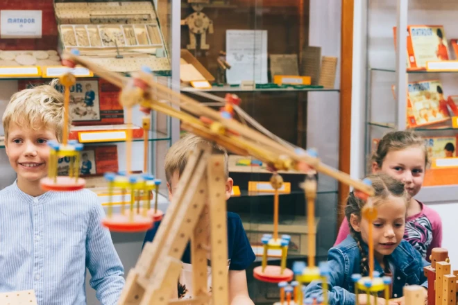 Kinder mit Matador-Bauwerken aus Holz.