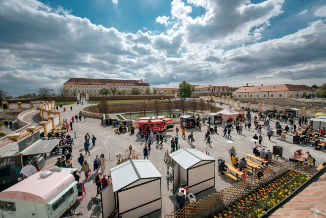Blick auf einen Markt mit kleinen Ständen, der vor Schloss Hof aufgebaut ist und den einige Personen besuchen,