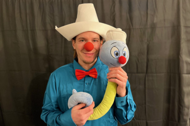 Foto von einem Clown der ein Stofftier in den Händen hält.