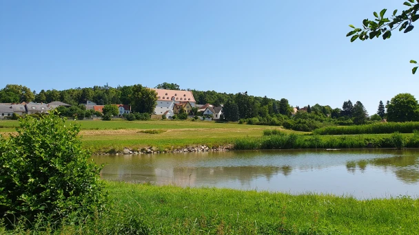 Blick über den Teich auf Häuser in Geras umgeben von Grün.