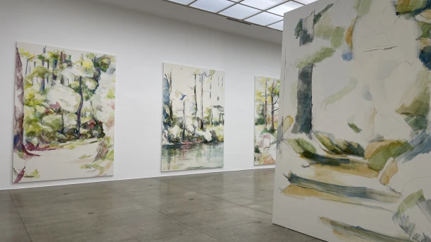 Blick durch den Ausstellungsraum auf grün-weiße Kunst.