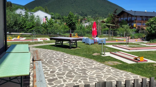 Minigolfbahnen vor der Bergkulisse bei Sonnenschein.