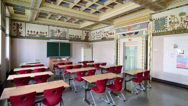Ein Klassenzimmer der Stilklassen mit roten Stühlen und Tischen.
