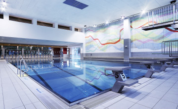 Blick auf einen Innenpool mit Starthockern und weiter hinten einem Sprungturm.