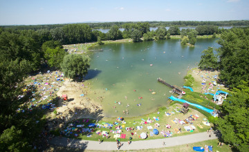 Blick aus der Vogelperspektive auf das naturbelassene Aubad und dem Ufer, auf dem sich viele Menschen befindne