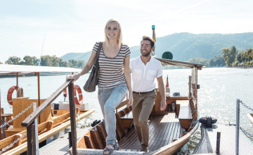 Ein junges Paar steigt aus einem Boot auf den Steg und sieht dabei sehr glücklich aus