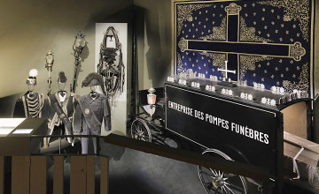 Blick auf einen alten Leichenwagen mit weiteren Requisiten rund um das Thema Trauer und Tod