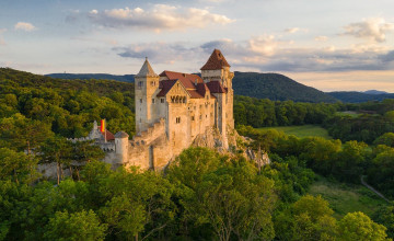 Blick auf die Burg Liechtenstein, die sich mit mehreren Türmen auf einer Anhöhe zwischen Wäldern erhebt,