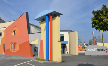 Blick auf ein Gebäude mit verschieden Fenstern und verschiedenen geometrischen Formen und Farben.