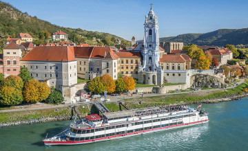 Blick auf ein Schiff DDSG Blue Danube Schiffahrt mit der eindrucksvollen blauen Kirch von Dürnstein im Hintergrund