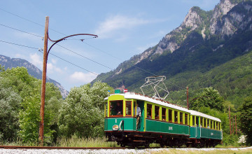 Blick auf die Höllentalbahn, die vor einer Bergkulisse fährt.