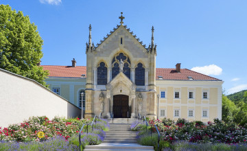 Blick auf das Jagdschloss, vor dem eine breite Treppe hinaufgeht mit einem Blumenbeet links und rechts davon.