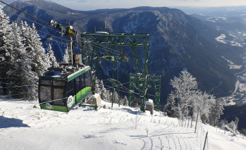 Blick von oben auf die Gondel der Rax-Seilbahn in einer Winterlandschaft.
